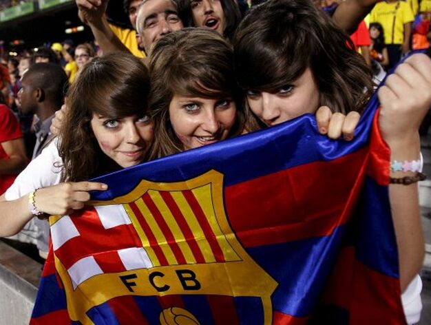 Tres aficionadas, con una bandera azulgrana con el escudo del FC Barcelona.