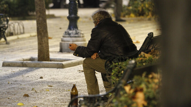 Un hombre sentado en el bando de un céntrico parque de Granada.