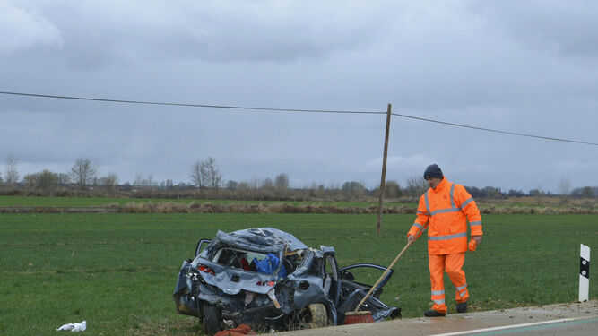 Un operario limpia la zona en la que se ve el coche destrozado a la altura de Villaturde, en Palencia.