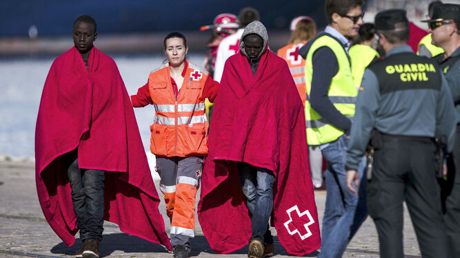 Dos de los inmigrantes junto a personal de la Cruz Roja y Guardia Civil.