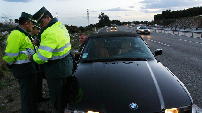 La Guardia Civil revisa los documentos de un coche parado.