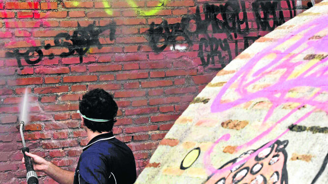 Un operario del Ayuntamiento limpia las paredes de pintadas en el barrio del Albaicín