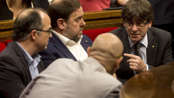 Puigdemont charla con Junqueras, Turull y Romeva durante el pleno celebrado ayer en el Parlamento de Cataluña.