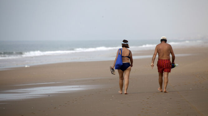 Una pareja camina por la arena firme de la playa.