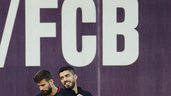 Luis Suárez, con Piqué detrás, calienta al inicio del entrenamiento de ayer.