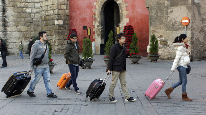 Un grupo de turistas, maleta en mano, pasa por delante de la Puerta del León del Real Alcázar.