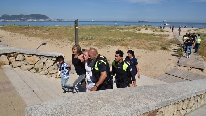 La Policía acompaña a los familiares del pequeño mientras abandonan la playa.