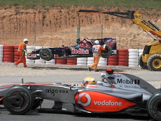 En primer plano, Lewis Hamilton. Al fondo, la gr&uacute;a se lleva el coche de Bourdais.

Foto: Reuters / AFP Photo / EFE