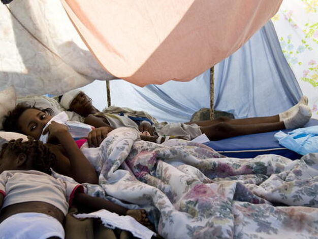 Unas ni&ntilde;as supervivientes descansan en el parking del Hospital General de Puerto Pr&iacute;ncipe.

Foto: Agencias