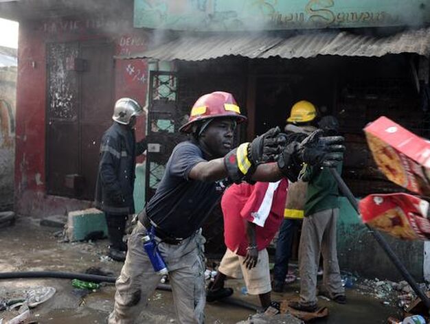 Un bombero trata de sofocar un fuego, mientras otro recoge alimentos.

Foto: Agencias