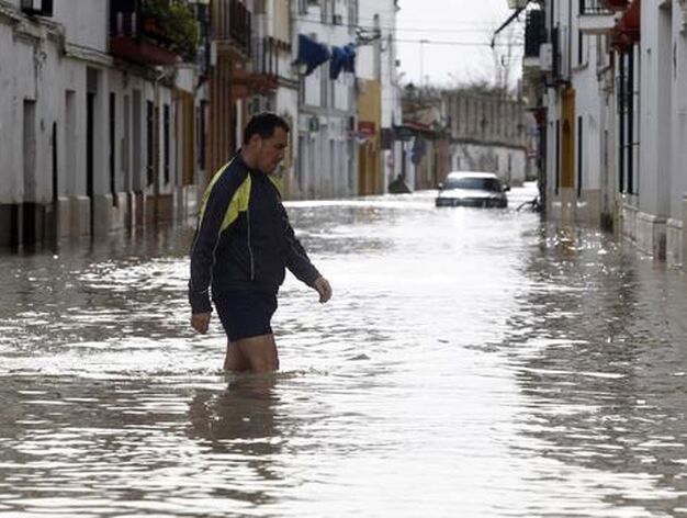 Un vecino intenta caminar por las inundadas calles de &Eacute;cija y un coche se qeuda atrapado en el agua.

Foto: Antonio Pizarro