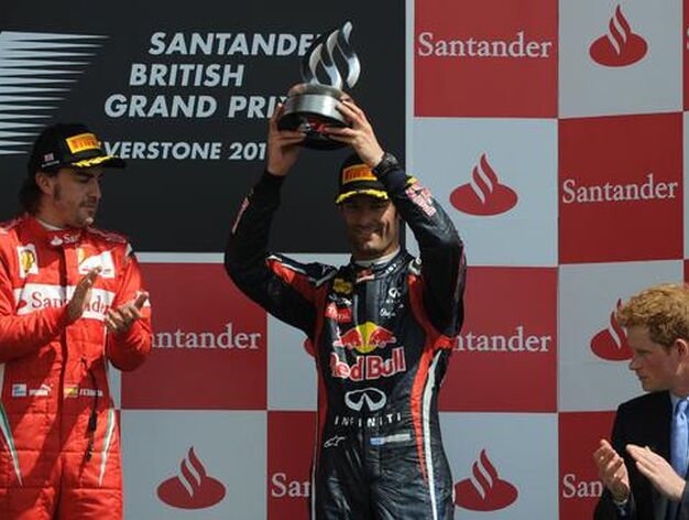 Mark Webber recoge su trofeo como tercer clasificado en el Gran Premio de Gran Breta&ntilde;a, junto a Fernando Alonso, ganador de la carrera, y el pr&iacute;ncipe Harry.

Foto: AFP Photo