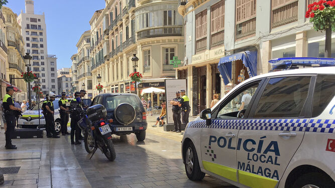 El vehículo en medio de la calle Larios rodeado por la Policía Local.