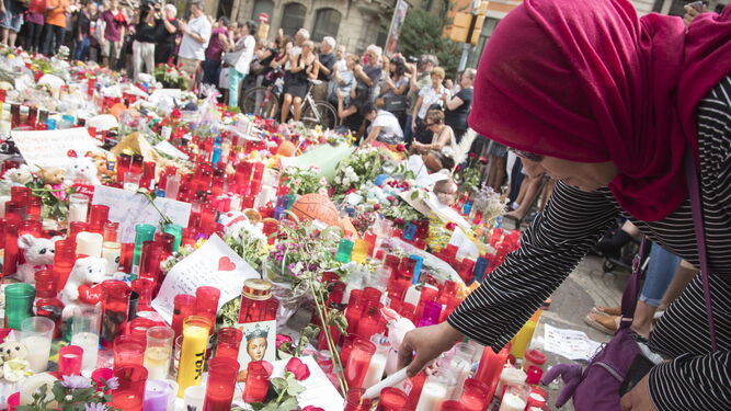 Una mujer enciende una vela en homenajes a las víctimas en el mosaico del suelo de Joan Miró.