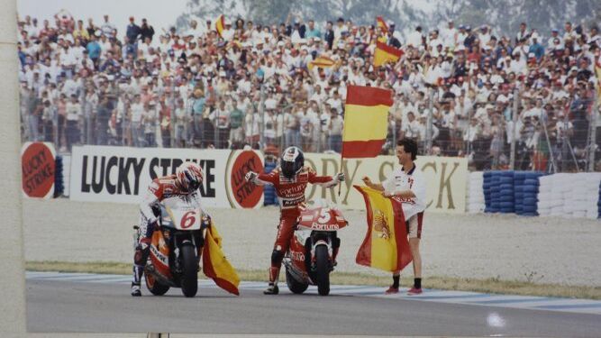 Alberto Puig toma una bandera de España para celebrar su triunfo en Jerez el 7 de mayo de 1995, junto a un Crivillé que también subió al podio
