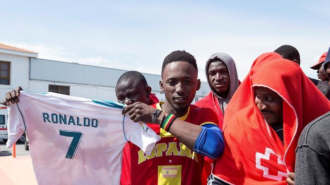 Uno de los inmigrantes muestra una camiseta del Real Madrid a su llegada al Puerto de Motril.