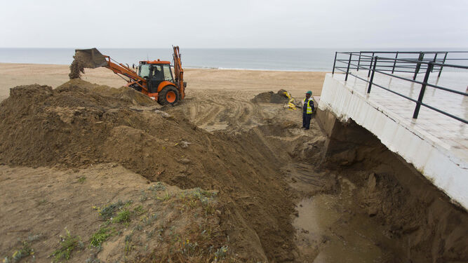 Una excavadora retira arena acumulada por la lluvia y el viento en el Paseo Marítimo de La Antilla.