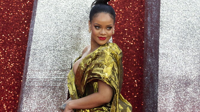 Rihanna luce un vestido dorado de Poiret cuyo tejido arrugado imita la textura del papel, drapeado y de largo asim&eacute;trico. Una elecci&oacute;n muy en la l&iacute;nea atrevida de la cantante y actriz, que completa su estilismo con sandalias y clutch dorados.