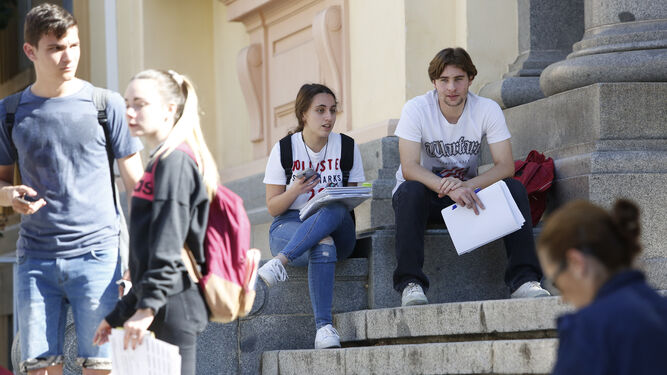 Estudiantes descansan y repasan a las puertas de la universidad antes de seguir examinándose.