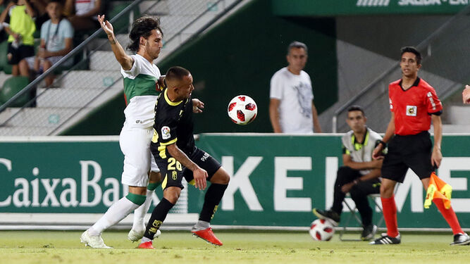 El delantero colombiano aguanta la presión de un defensa ilicitano ante la mirada del asistente.