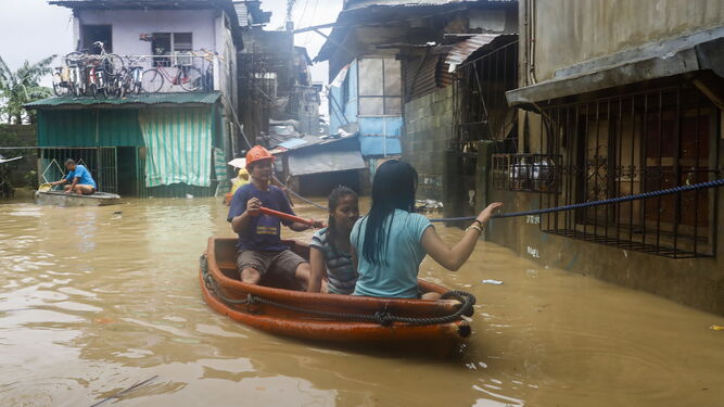 Vecinos de la localidad filipina de San Mateo abandonan ayer en barca sus domicilios inundados por el agua.