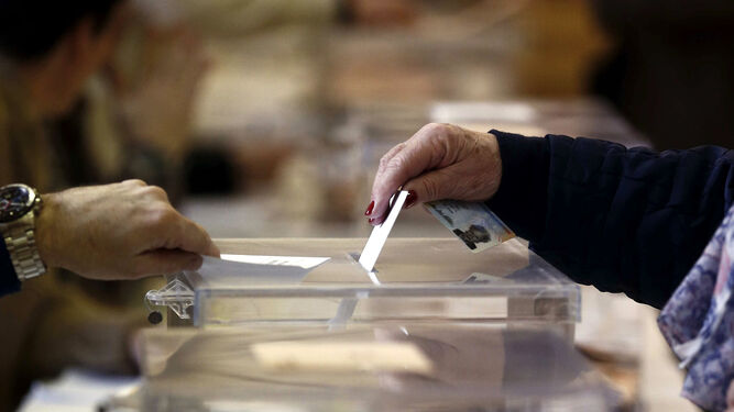 Una mujer introduce su voto en una urna.