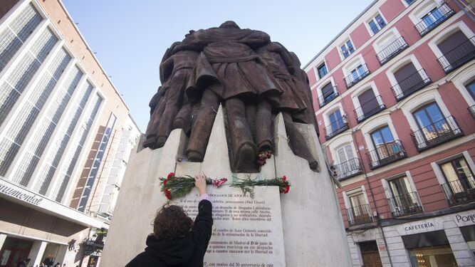 Una mujer coloca un ramo de flores en el monumento al crimen de Atocha