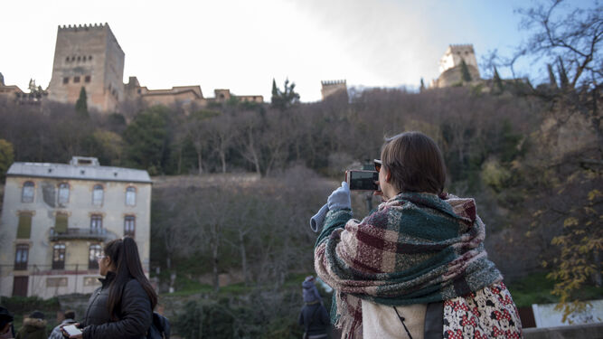 Una joven realiza una foto a la Alhambra desde el Paseo de los Tristes.