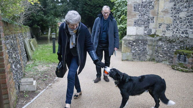 May juega con un perro antes de entrar en una iglesia junto a su marido.