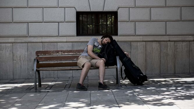 Un músico se duerme en un banco de la Plaza del Carmen