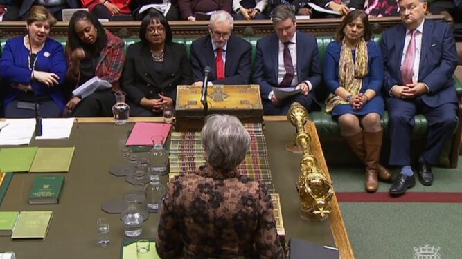 Theresa May (de espaldas) se dirige a la Cámara de los Comunes con Jeremy Corbyn enfrente.