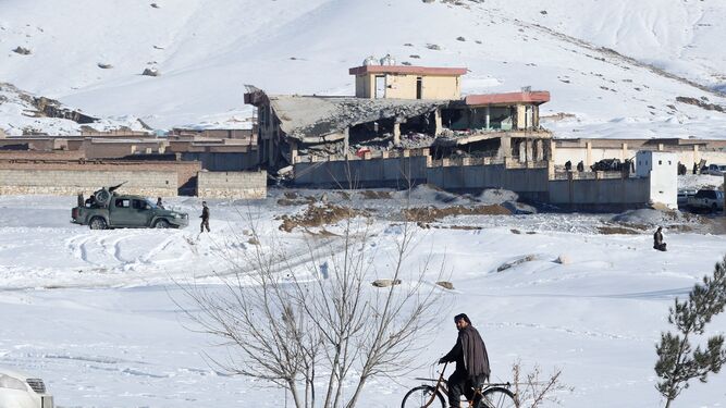 Un hombre pasea en bicicleta junto al edificio atacado de la principal agencia de seguridad afgana en Wardak.