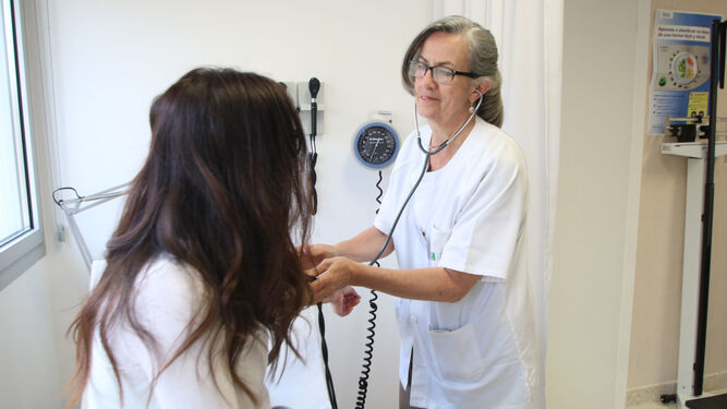 Una médico mide la tensión arterial de una paciente en una consulta.