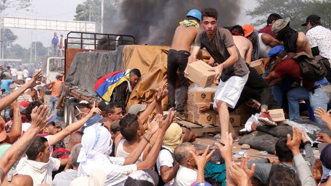 Personas intentan sacar parte de la ayuda humanitaria que se encuentra un camión que fue quemado, este sábado, en Ureña (Venezuela).