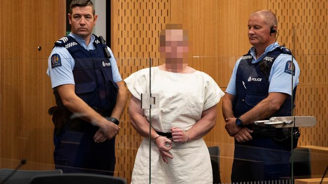 Tarrant (con la cara pixelada), escoltado por dos policías en una reciente declaración en Christchurch.