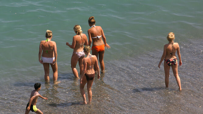 Un grupo de jóvenes se disponen a bañarse en una playa andaluza.