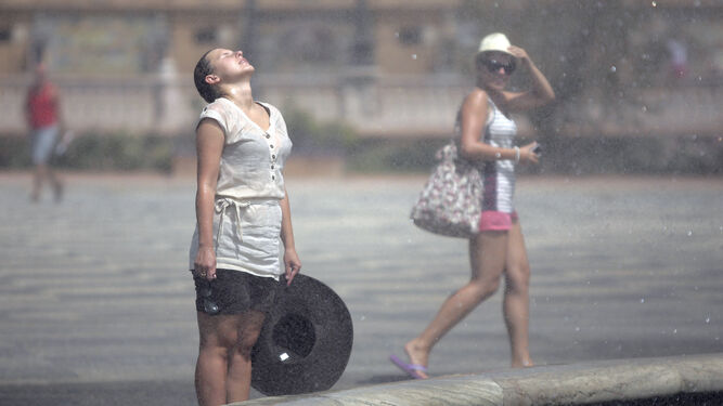Una mujer se refresca junto a una fuente de la Plaza de España de Sevilla.