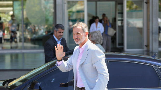 El rey Felipe VI  saluda a la prensa tras bajar del coche.