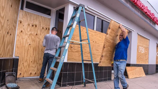 Empleados de una tienda de Miami Beach cubren el local con tablones de madera por la llegada del huracán Dorian.