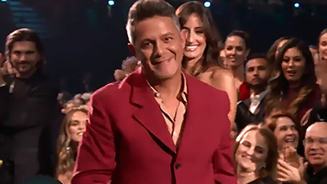Alejandro Sanz sube a recoger un Grammy, mientras detrás su novia le aplaude.