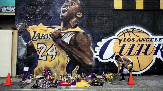 Flores y velas ante un mural de Kobe Bryant
