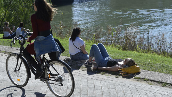 Varias jóvenes disfrutan del sol y las temperaturas primaverales junto al río.