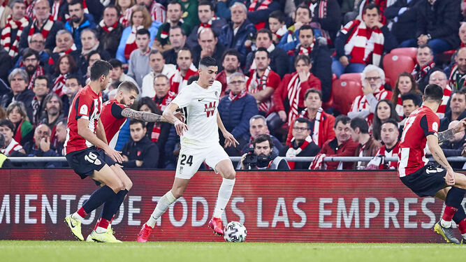 Carlos Fernández protege el balón ante la presión de Íñigo Martínez y Mikel Vesga