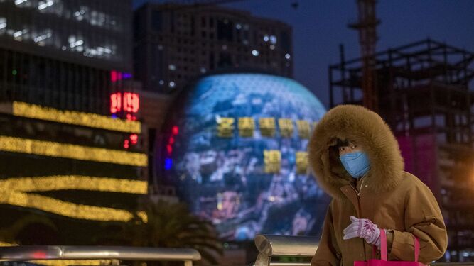 Una mujer se protege con una mascarilla en el centro financiero de Shanghái.