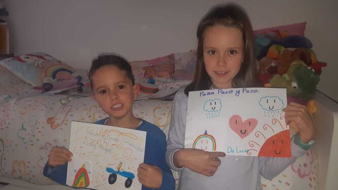 Ángel y Lucía, con los dibujos que le han hecho a sus vecinos para agradecerles el regalo.