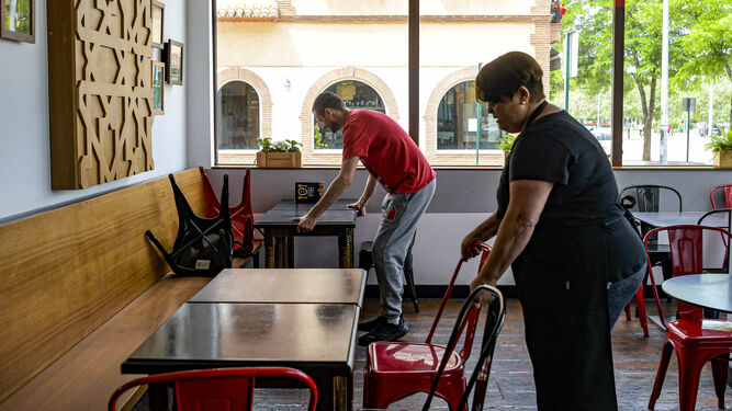 Trabajadores de un bar preparan las mesas con distancia entre ellas para poder abrir mañana