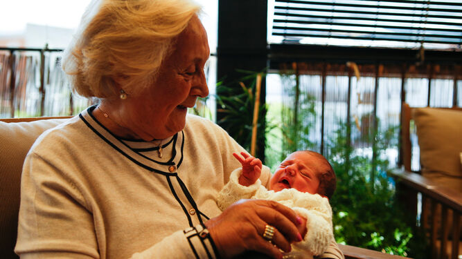 Ángeles García, la bisabuela de Jimena, sonríe mientras la coge en brazos.