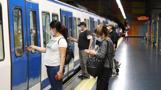 Varios pasajeros abreiendo la puerta de un tren del Metro de Madrid.
