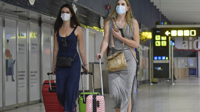 Dos jóvenes con mascarillas en el aeropuerto de Sevilla.
