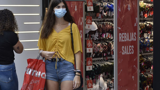 Una joven sale de una tienda con mascarilla.